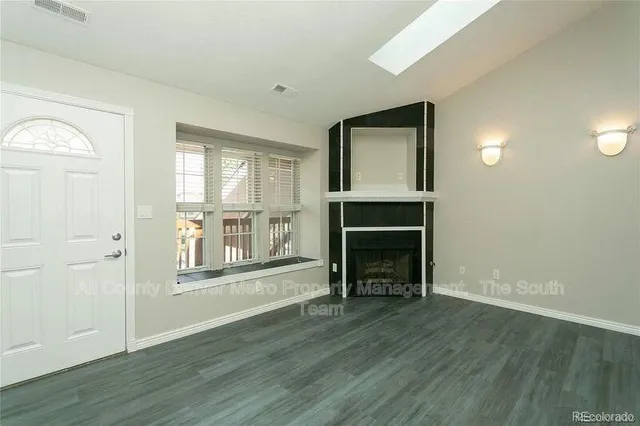 an empty room with wooden floor fireplace and windows