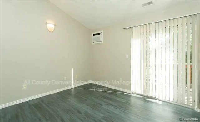an empty room with wooden floor and windows with curtains