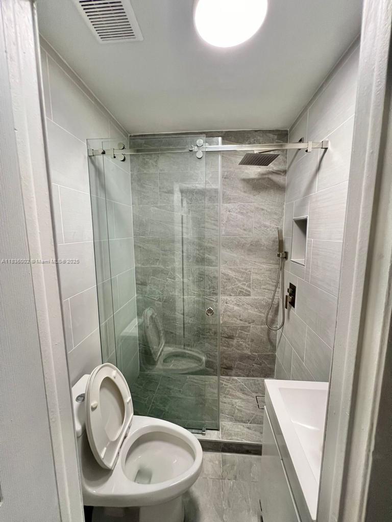 2165 Southwest 47th Street, Unit 2 Dania Beach, FL 33312 - Photo 5 of 10 a bathroom with a granite countertop bathtub shower sink and toilet