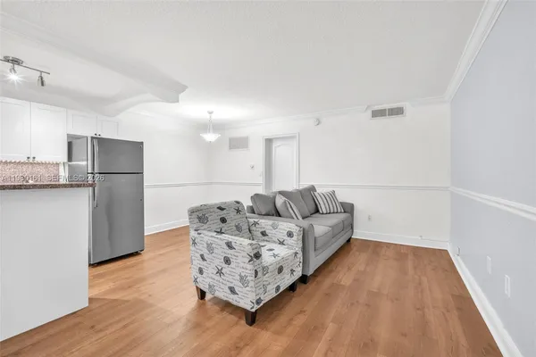 a living room with furniture and a refrigerator