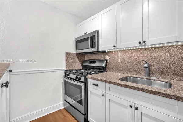 a kitchen with granite countertop a sink dishwasher stove and microwave with wooden floor