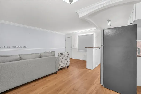 a living room with furniture and a refrigerator