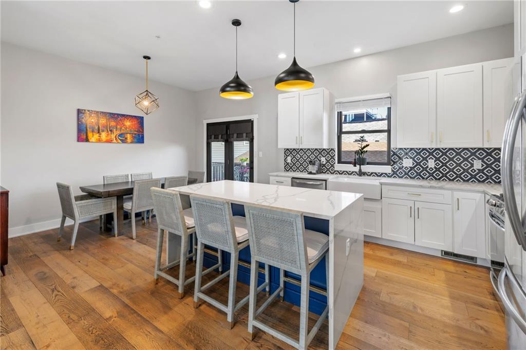 734 Middle Street Pittsburgh, PA 15212 - Photo 10 of 46 a kitchen with stainless steel appliances granite countertop a sink a stove a dining table and chairs with wooden floor