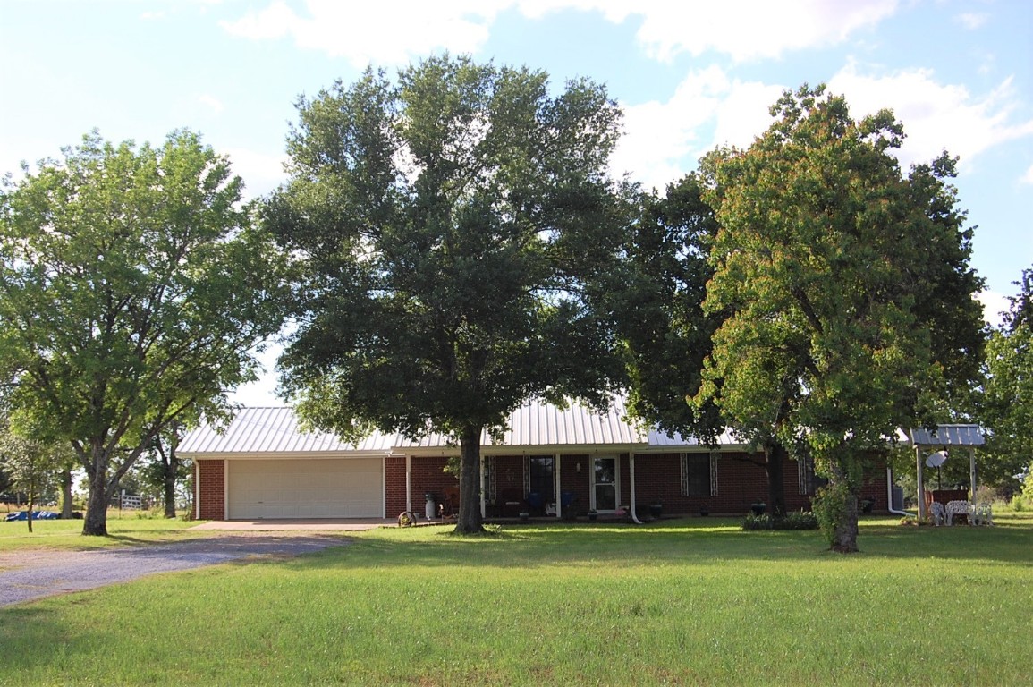 a view of a house with a big yard and large trees