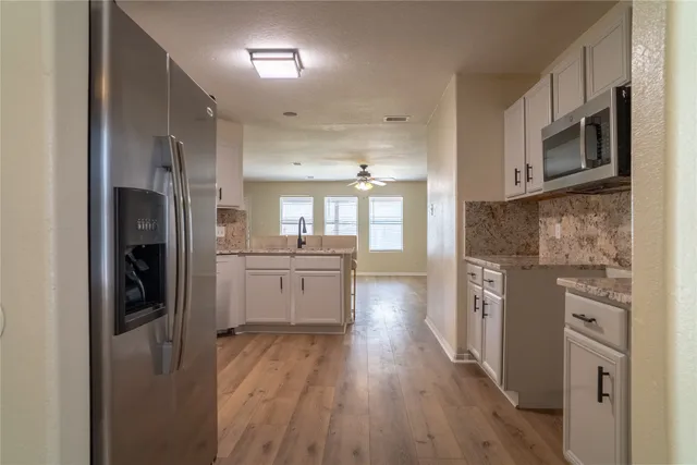a kitchen with stainless steel appliances a refrigerator sink and wooden floor