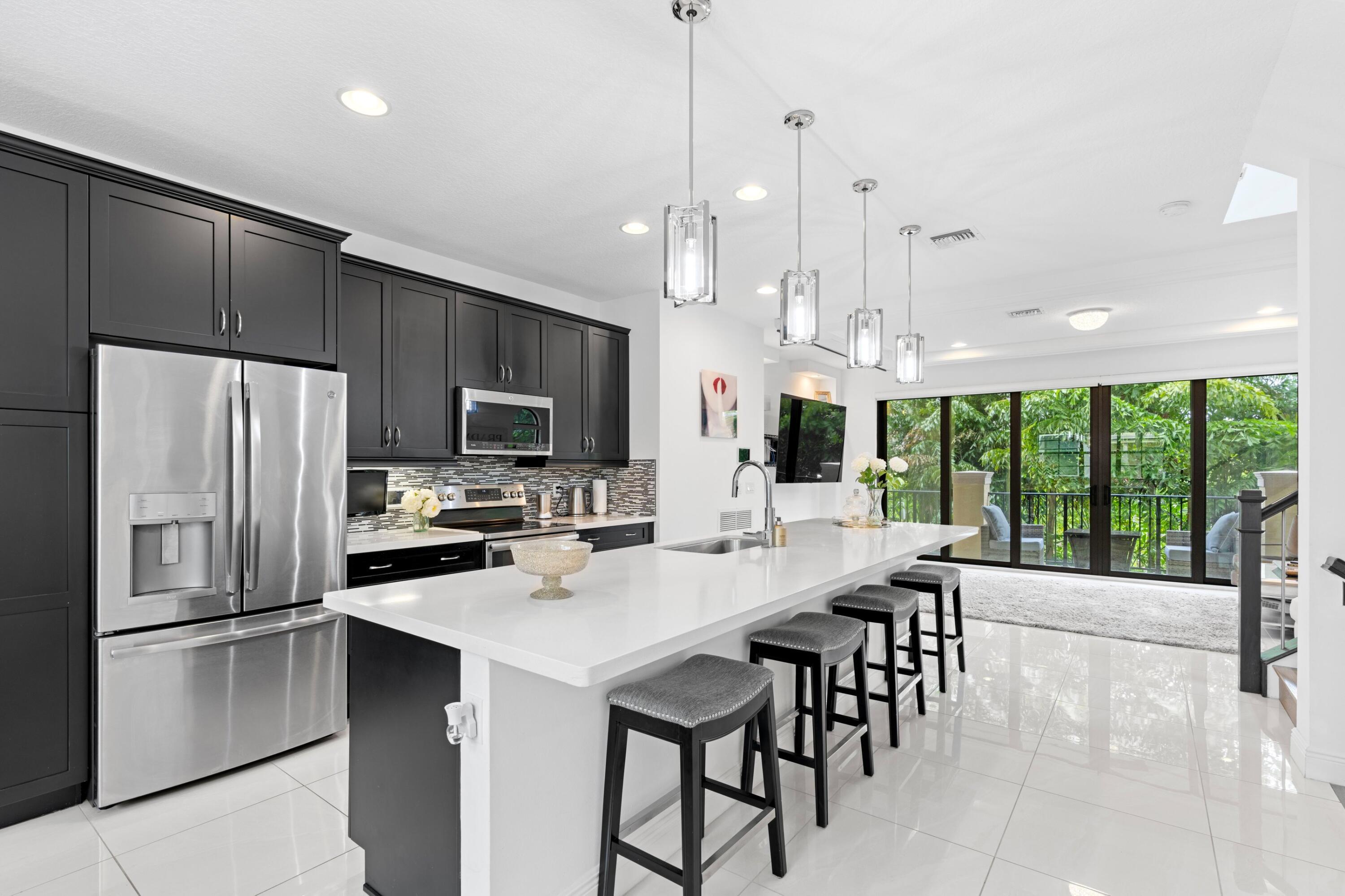 a kitchen with stainless steel appliances a table chairs refrigerator and microwave