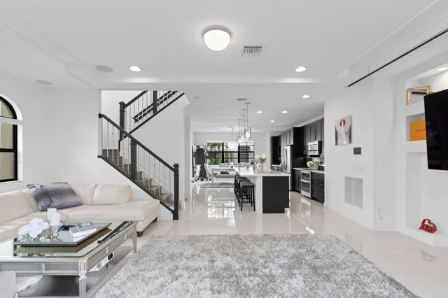 a living room with furniture kitchen view and a wooden floor