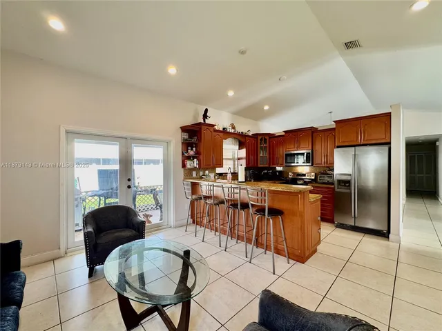 a kitchen with stainless steel appliances kitchen island granite countertop a refrigerator a stove a sink a dining table and chairs