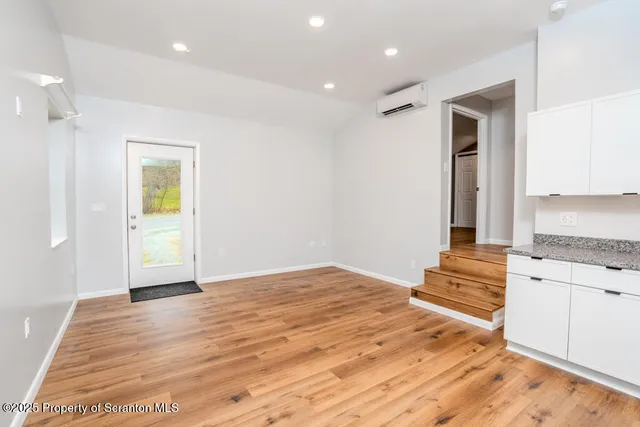 a view of an empty room with window and wooden floor
