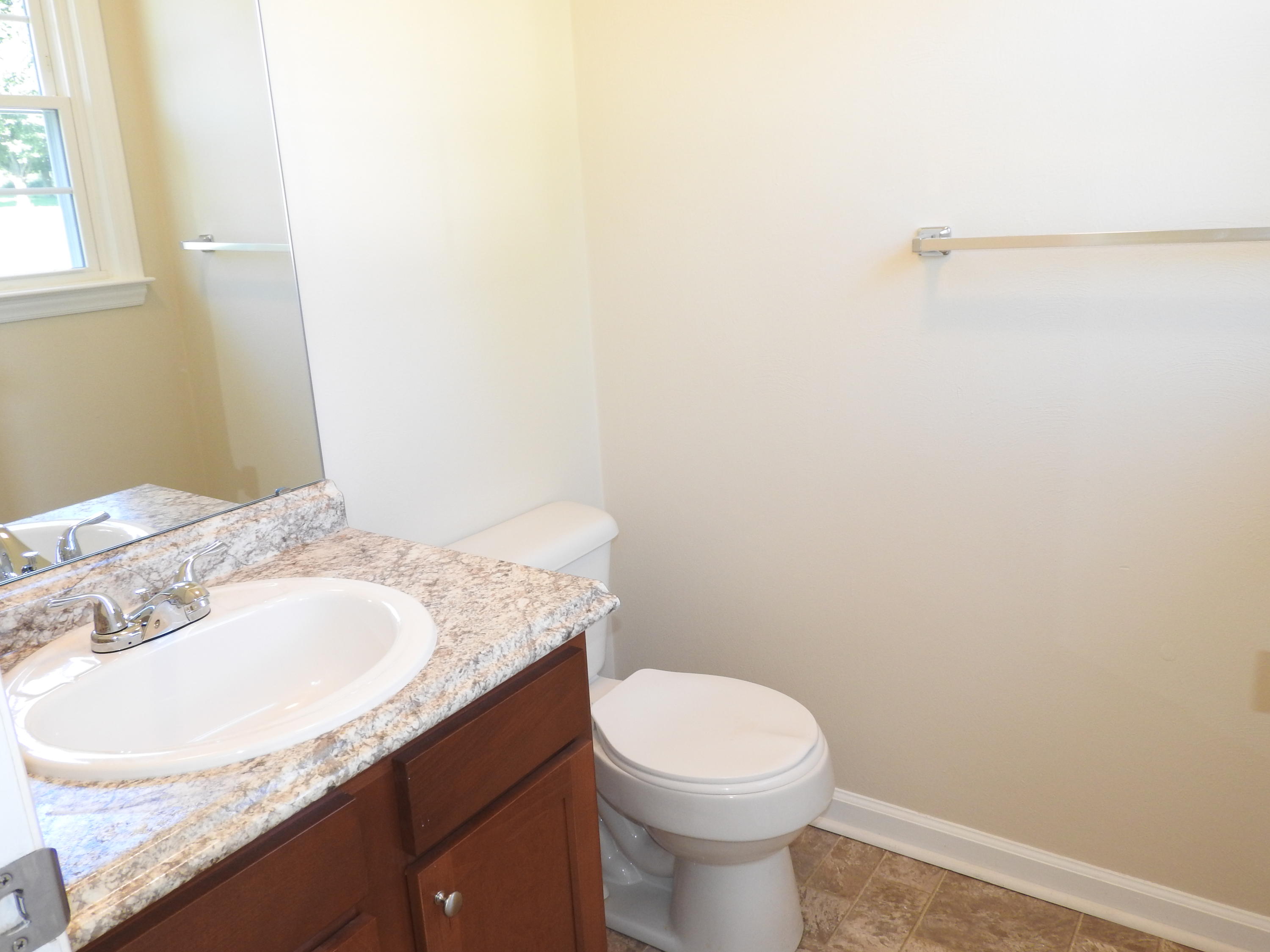 1873 Morgans Mill Road Goodview, VA 24095 - Photo 12 of 26 a bathroom with a granite countertop sink a toilet and a mirror