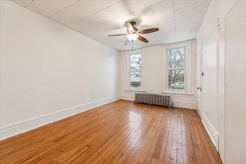 an empty room with wooden floor fan and windows