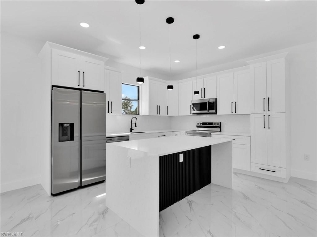 3419 8th Street Southwest Lehigh Acres, FL 33976 - Photo 11 of 29 a kitchen with stainless steel appliances a refrigerator sink and white cabinets