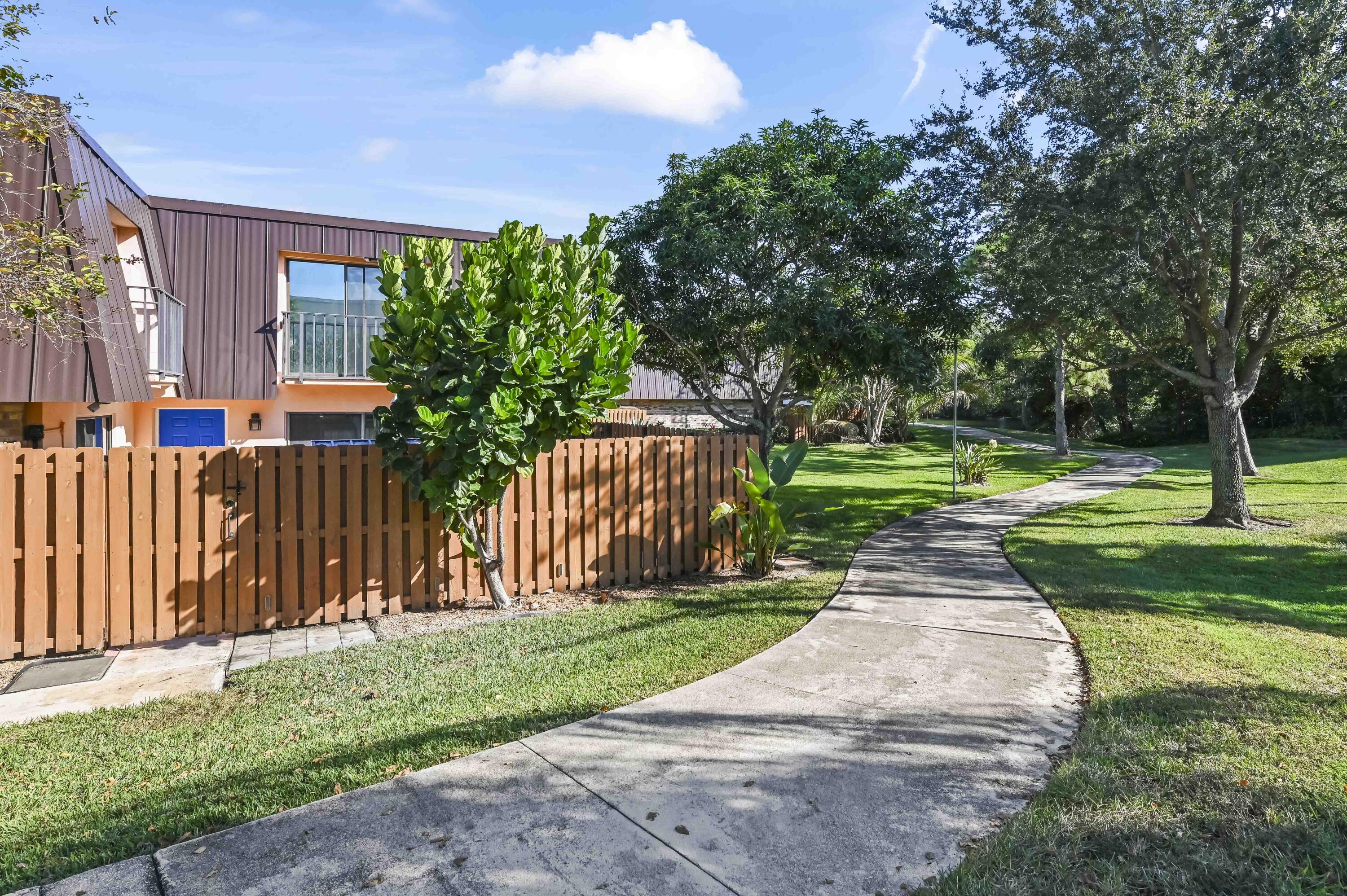 5708 Southeast Windsong Lane Stuart, FL 34997 - Photo 2 of 41 a front view of a house with a yard table and chairs