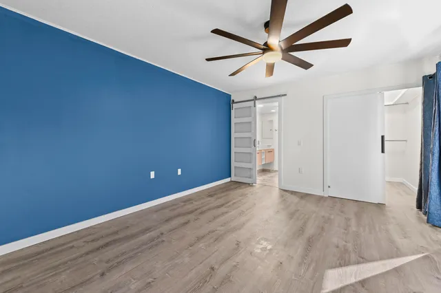an empty room with wooden floor and a ceiling fan