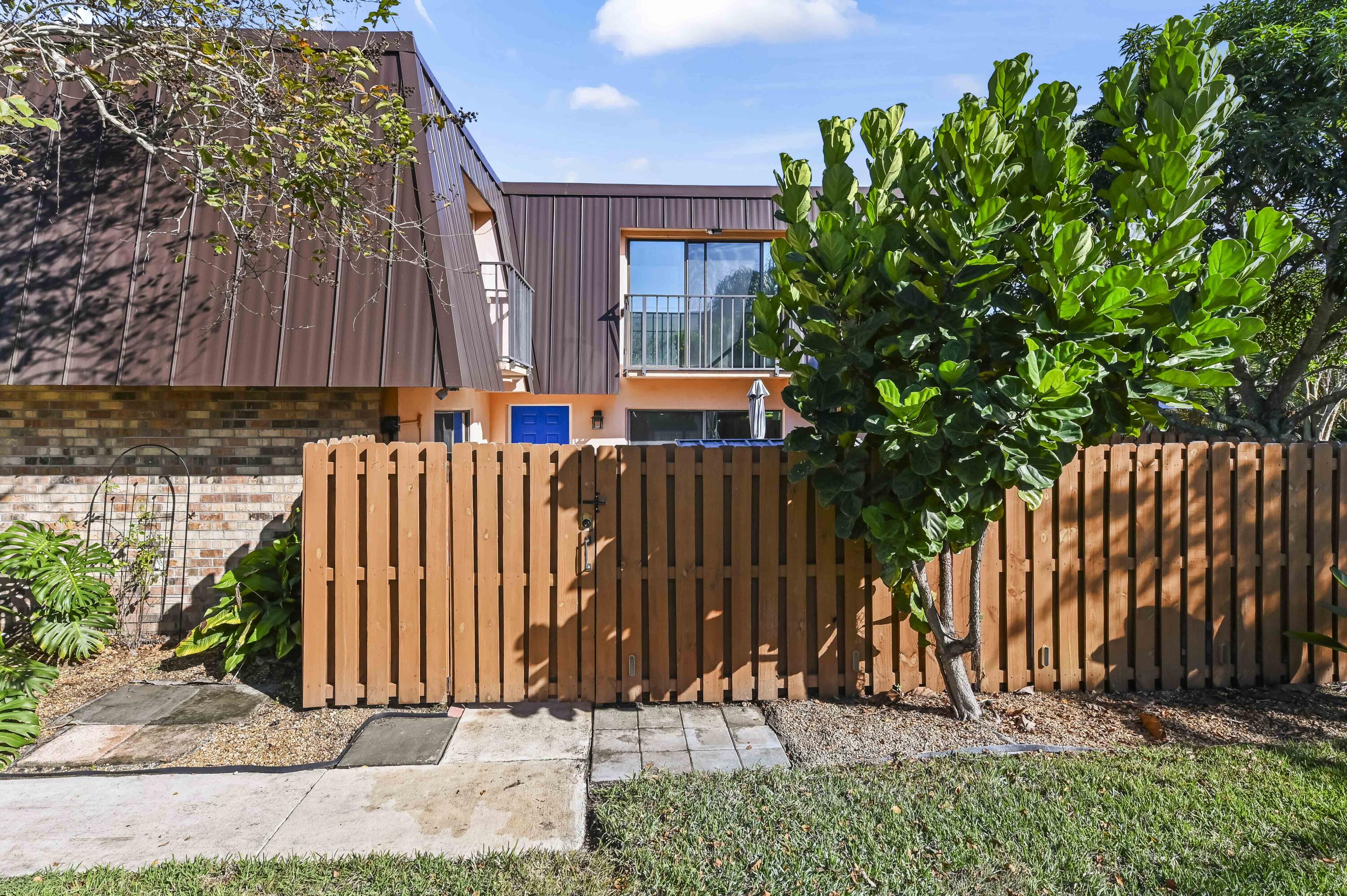 5708 Southeast Windsong Lane Stuart, FL 34997 - Photo 3 of 41 a view of a house with a small yard and wooden fence