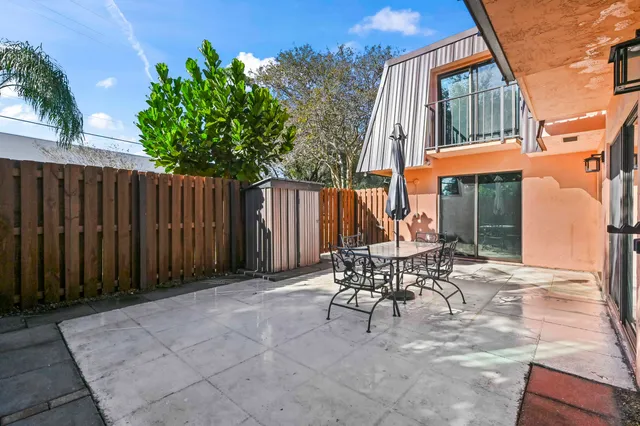 a patio with table and chairs and potted plants