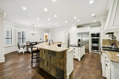 a kitchen with stainless steel appliances granite countertop a lot of cabinets and wooden floor