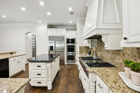 a kitchen with stainless steel appliances kitchen island granite countertop a stove and white cabinets