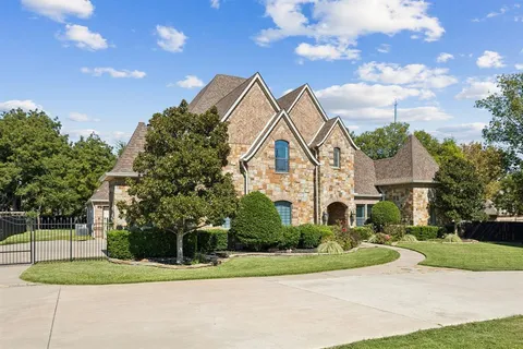 a view of a white house next to a yard with big trees