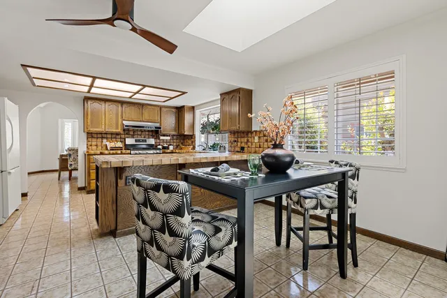 a kitchen with stainless steel appliances kitchen island granite countertop a table chairs in it and wooden floors