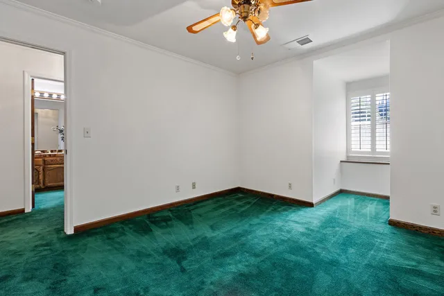 an empty room with a chandelier fan and windows