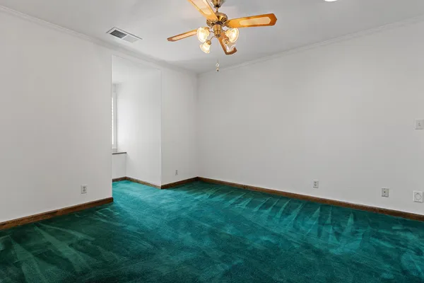 a view of an empty room with chandelier fan