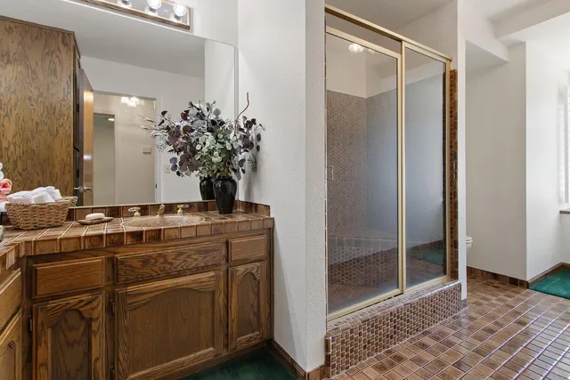 a view of a bathroom with mirror and shower