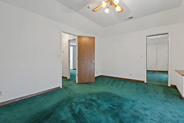 an empty room with closet and a chandelier fan