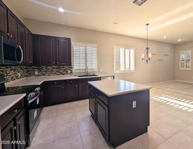 a kitchen with stainless steel appliances wooden cabinets a sink a stove a refrigerator a center island and a oven