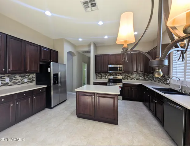 a kitchen with stainless steel appliances granite countertop a sink refrigerator and cabinets