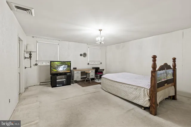 a spacious bedroom with a bed and a chandelier