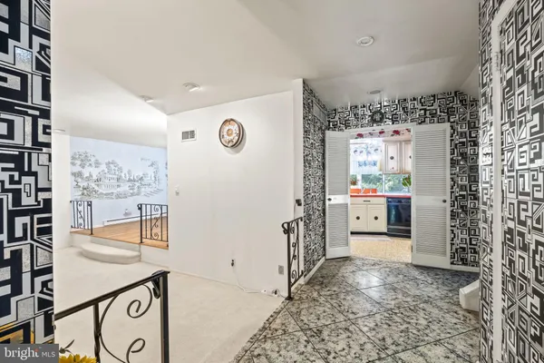 a view of a hallway to room with rug and wall paintings