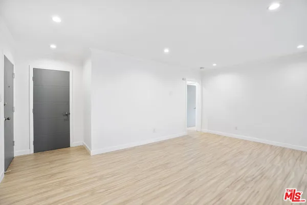 a view of an empty room with wooden floor and closet