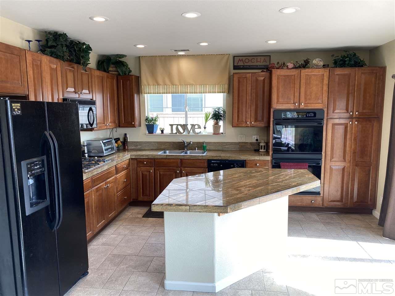 2150 Overland Road Reno, NV 89521 - Photo 5 of 19 a kitchen with kitchen island granite countertop wooden cabinets a refrigerator and a sink