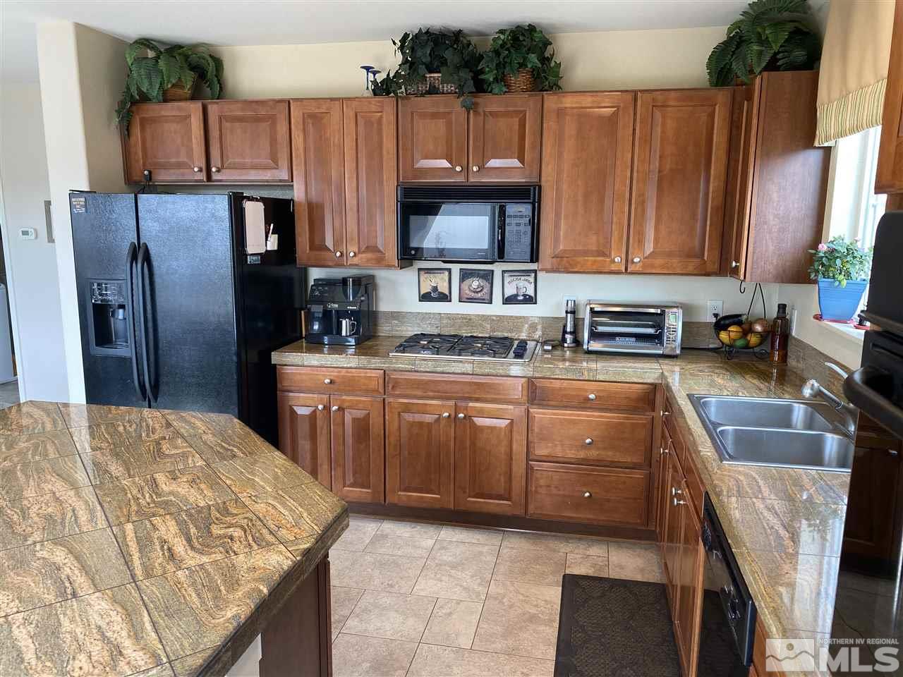 2150 Overland Road Reno, NV 89521 - Photo 6 of 19 a kitchen with stainless steel appliances granite countertop a refrigerator a stove a sink dishwasher and wooden cabinets with a lots of counter space