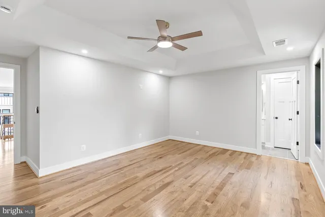 a view of an empty room with wooden floor and a kitchen