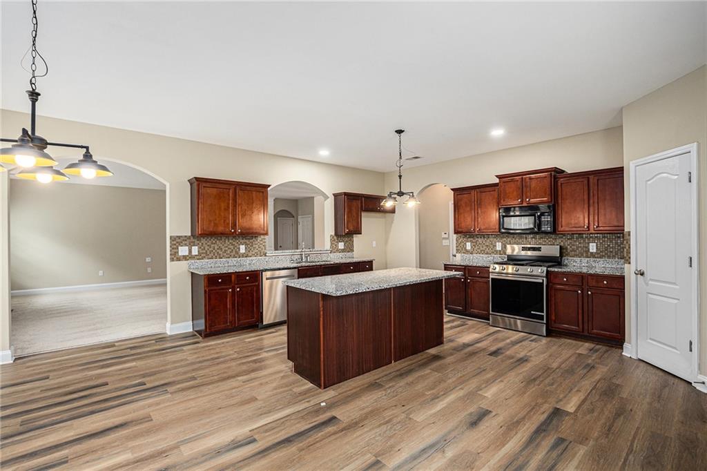 6054 Locklear Way Douglasville, GA 30134 - Photo 14 of 36 a large kitchen with stainless steel appliances kitchen island granite countertop a stove refrigerator and a sink