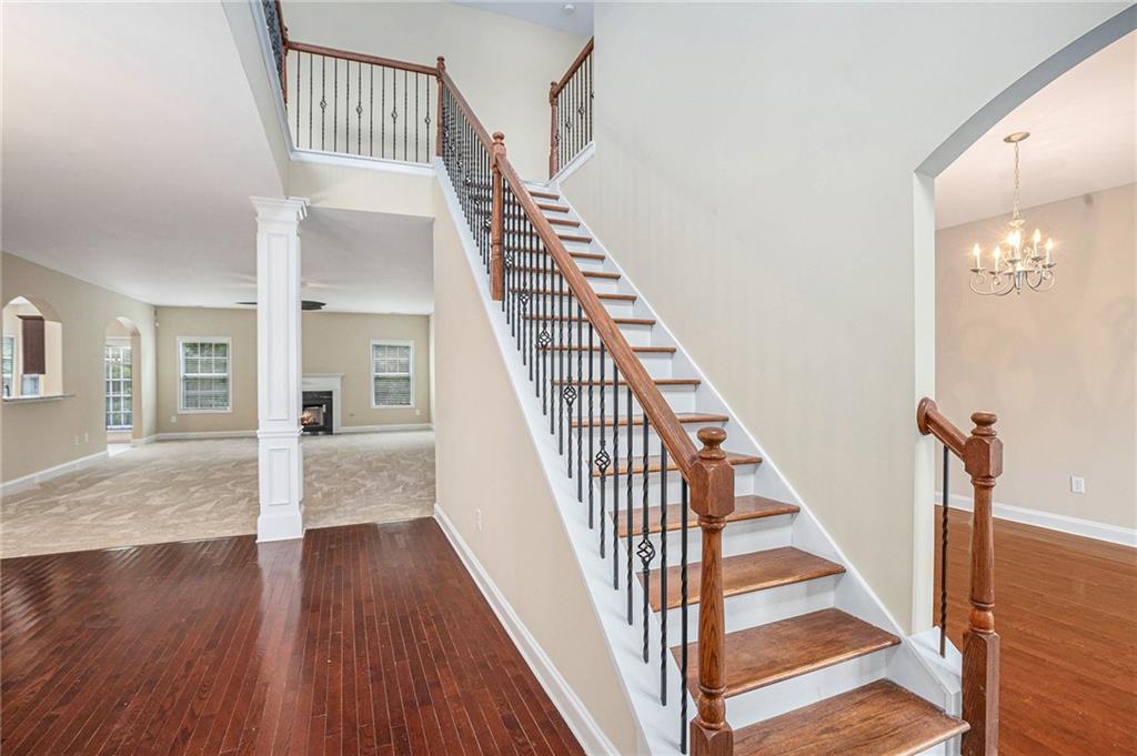 6054 Locklear Way Douglasville, GA 30134 - Photo 17 of 36 a view of staircase with wooden floor and a chandelier