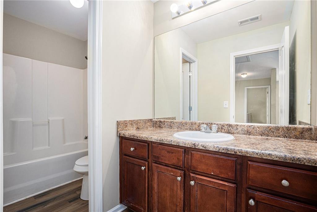 6054 Locklear Way Douglasville, GA 30134 - Photo 29 of 36 a bathroom with a granite countertop sink a toilet and bathtub