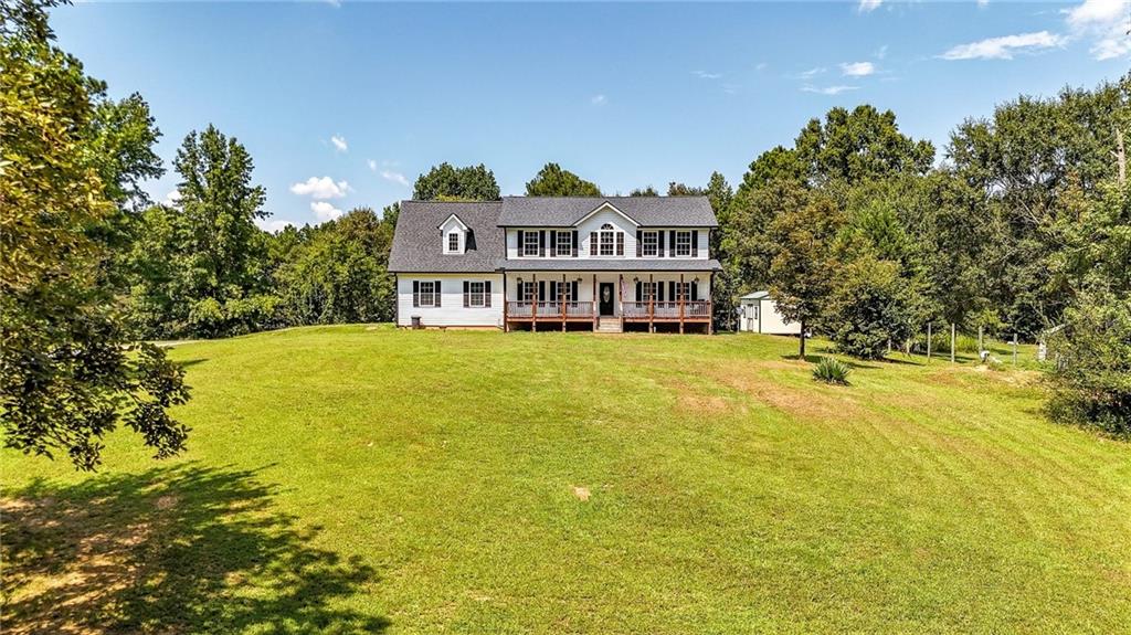a view of a house with a big yard and large trees
