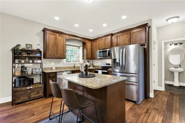 a kitchen with kitchen island granite countertop stainless steel appliances and wooden cabinets
