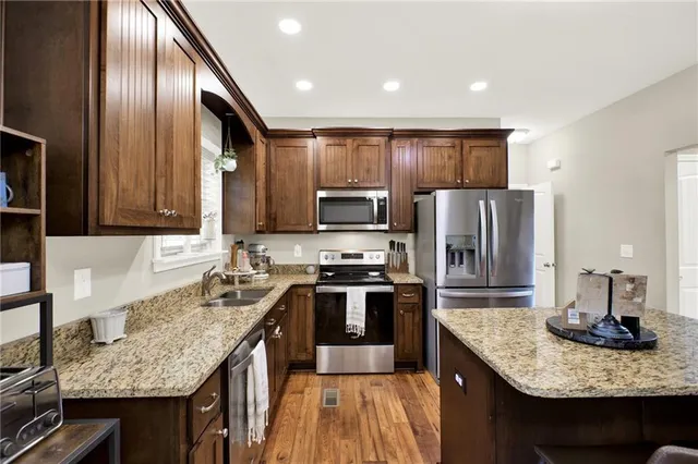 a kitchen with stainless steel appliances granite countertop a sink stove and cabinets