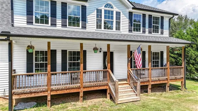 a view of a house with yard and trees in the background