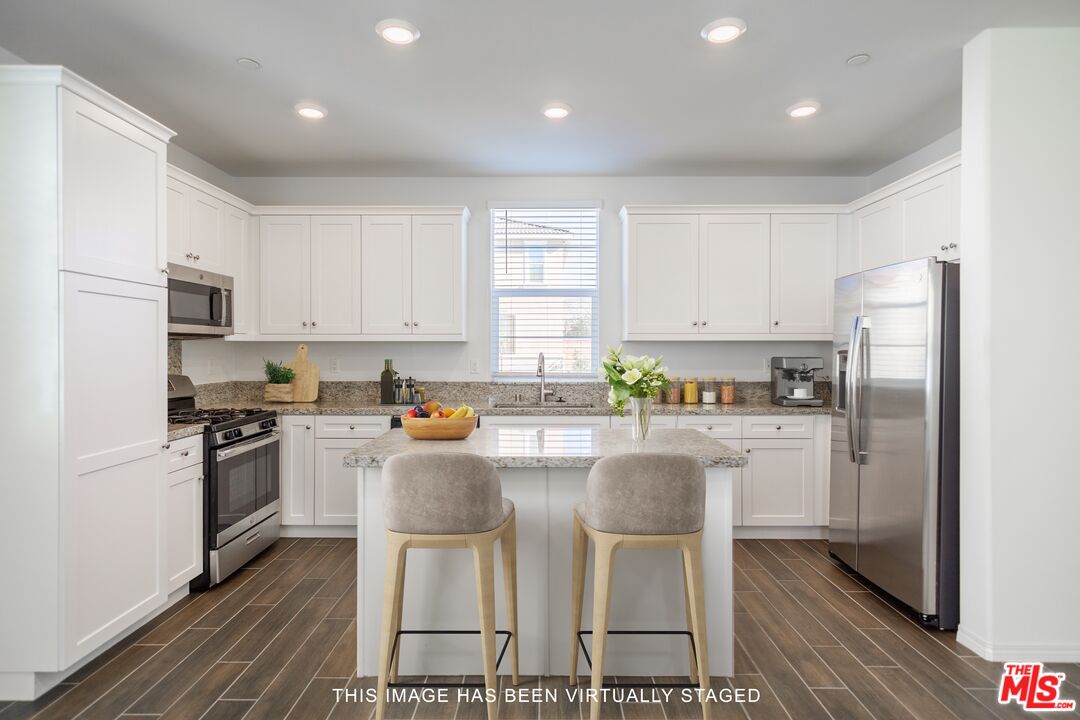 7935 Cold Creek Street Riverside, CA 92507 - Photo 8 of 45 a kitchen with stainless steel appliances granite countertop a refrigerator a stove top oven a sink dishwasher and white cabinets with wooden floor