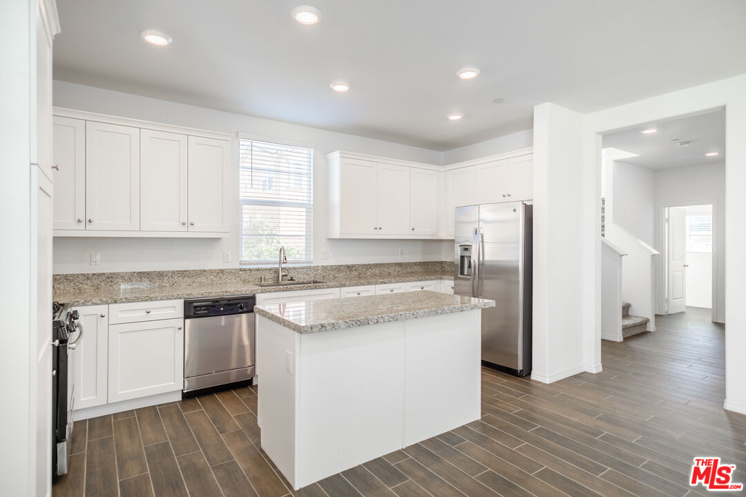 7935 Cold Creek Street Riverside, CA 92507 - Photo 9 of 45 a kitchen with stainless steel appliances granite countertop a stove a refrigerator a sink and white cabinets with wooden floor