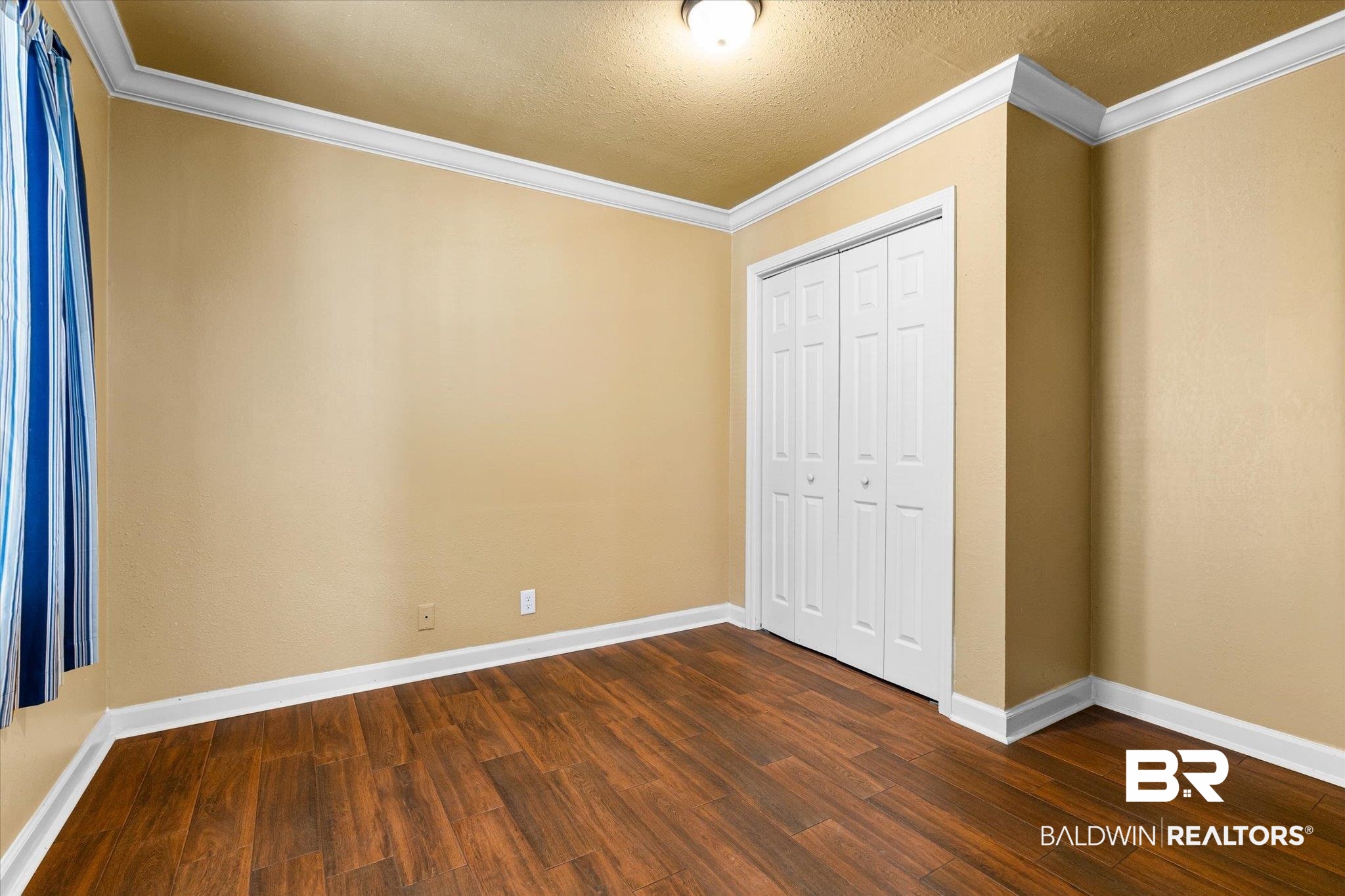 1310 Brown Street Mobile, AL 36604 - Photo 16 of 18 Unfurnished bedroom featuring a closet, crown molding, a textured ceiling, and dark hardwood / wood-style floors