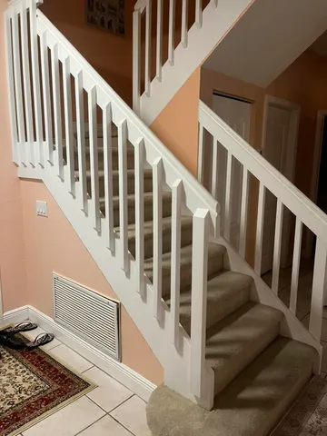 a view of staircase with railing and white walls