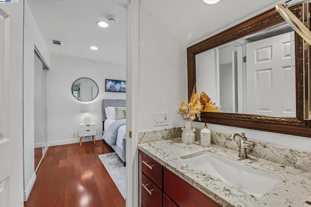 a en suite bathroom with a granite countertop sink and a mirror