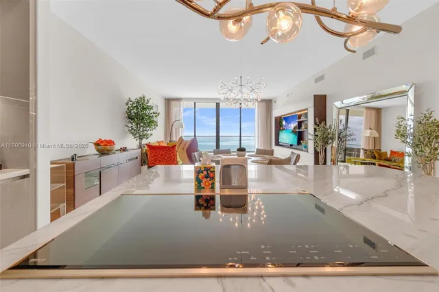 a dining room with furniture a chandelier and kitchen view