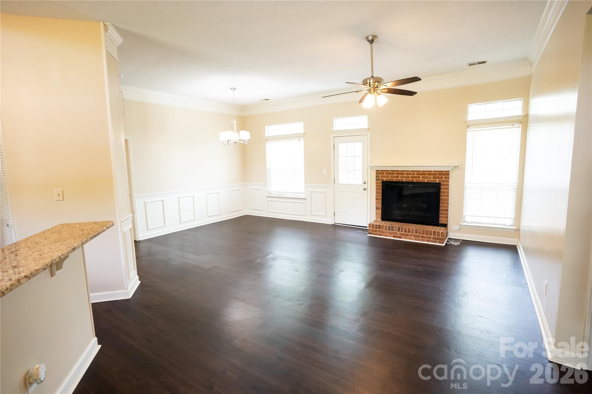 10737 Spruce Mountain Road Charlotte, NC 28214 - Photo 14 of 19 an empty room with wooden floor fireplace and windows